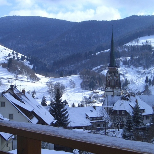 Balkon mit Panoramablick auf das verschneite Schönau mit dem Kirchturm der Maria Himmelfahrtskirche - 