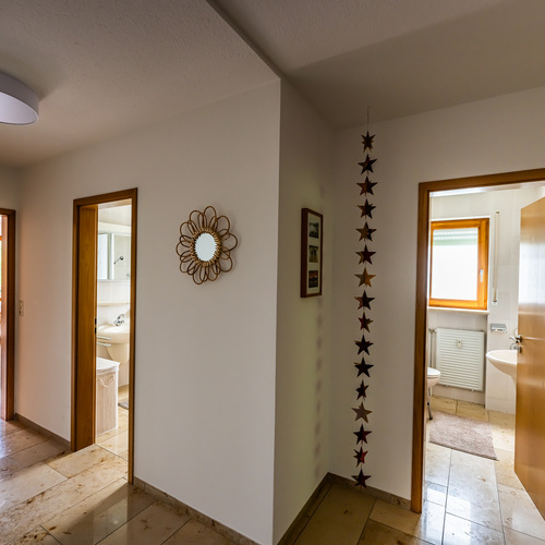 Blick vom Flur auf zwei geöffneteTüren des Badezimmers und der WC-Türe - 